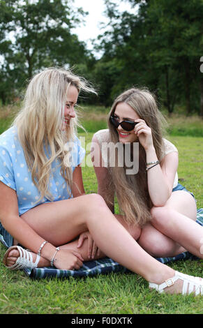 Deux adolescentes assis sur l'herbe en été, laughing Banque D'Images