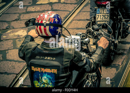 Motocycliste portant une veste en cuir noir avec Iron Maiden imprimé sur le dos, et un casque américain fla Banque D'Images