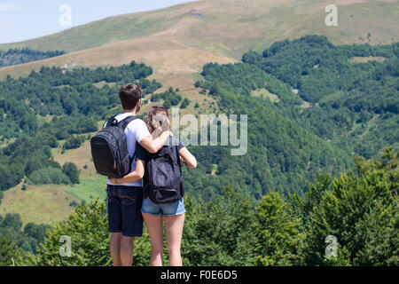 Couple de randonneurs avec des sacs debout à vue et bénéficiant d'une vue sur la vallée. L'activité commune du couple Banque D'Images