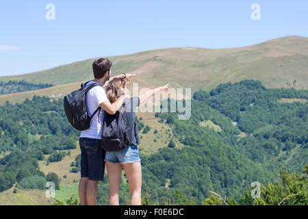 Couple de randonneurs avec des sacs debout à vue et bénéficiant d'une vue sur la vallée. L'activité commune du couple Banque D'Images