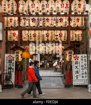 Les piétons à l'entrée et à l'intérieur de temple au marché Nishiki à Kyoto, au Japon. Lanternes japonaises accrocher à l'avant. Banque D'Images