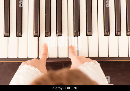 Close up de mains d'enfant qui joue du piano. Vue de dessus de la petite fille sur sa musique. Elle est juste en utilisant deux doigts. Banque D'Images