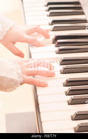 Close up de mains d'enfant qui joue du piano. Petite fille pratiquant sur sa musique. Banque D'Images