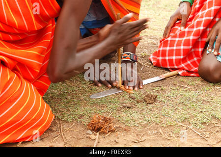 Les hommes de faire feu à l'aide de Masai une perceuse à main dans un village Masai, Masai Mara, Kenya. La base de l'encoche est conservé sur un couteau traditionnel Banque D'Images