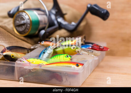 Les appâts de pêche libre dans la case wobbler avec reel et cap sur fond de bois avec selective focus Banque D'Images