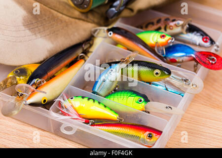 Les appâts de pêche libre dans la case wobbler avec reel et cap sur fond de bois avec selective focus Banque D'Images