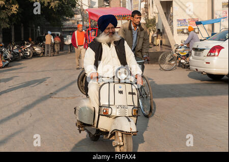 Amritsar, Punjab, India.Personnes âgées homme sikh avec moustache blanche équitation une Vespa scooter Bajaj impeccable portant chemise blanche et un pantalon. Banque D'Images