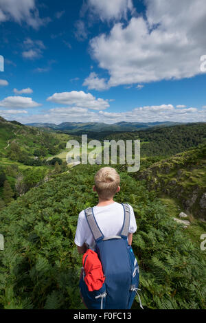 Un jeune garçon regarde l'horizon prêt pour une aventure en plein air dans le Lake District, Cumbria, Royaume-Uni Banque D'Images