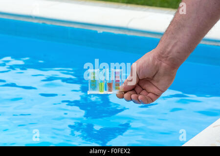 Testeur pour piscine dans une main contre le fond de la piscine. Banque D'Images