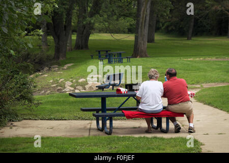 Senior couple having un déjeuner pique-nique sur un après-midi brumeux à Ferguson Township Park dans la région de East Lansing, Michigan, USA Banque D'Images