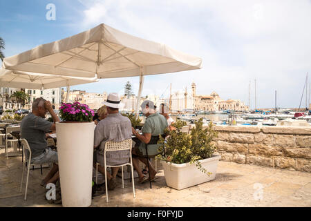 Les touristes de manger dehors le déjeuner à Otranto avec vue sur port de plaisance et la mer Adriatique Banque D'Images