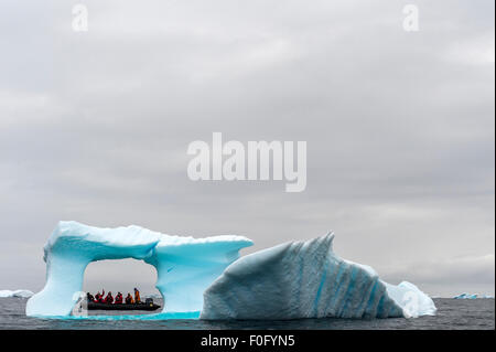 Iceberg bleu flottant dans la mer avec des pneumatiques tourisme dans l'arrière-plan Cierva Cove Péninsule Antarctique Antarctique Banque D'Images