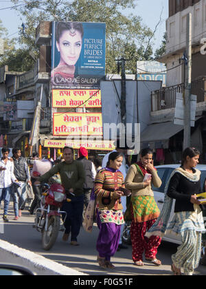 Amritsar, Punjab, en Inde. Scène de rue ; les piétons passant en dessous d'une annonce pour la "photo des mariées parfaite en anglais avec un signe jaune et rouge en punjabi ci-dessous. Banque D'Images