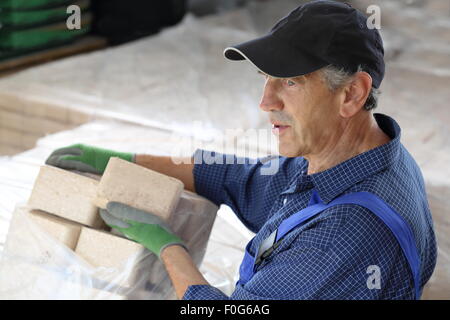 Un homme avec des bûches de bois dans un stockage Banque D'Images