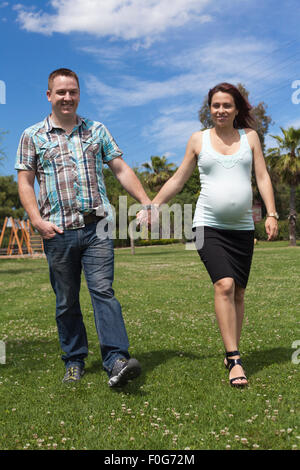 Happy pregnant couple en train de marcher ensemble dans le parc. Banque D'Images