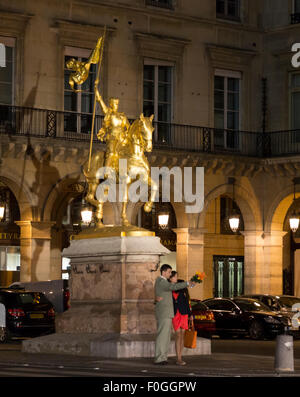 Vue de la nuit de couple standing in front of the illuminated statue de Jeanne d'Arc dans la place des Pyramides, Paris France Banque D'Images