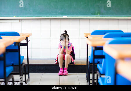 Le stress girl sitting et de pensée sur le plancher de la classe Banque D'Images