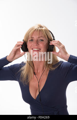 Attractive Woman holding les écouteurs à ses oreilles à écouter de la musique Banque D'Images