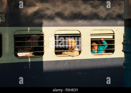 Kalka, Himachal Pradesh, Inde. Les passagers d'un train par l'intermédiaire de barreaux aux fenêtres. Banque D'Images