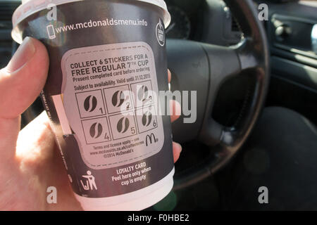 L'homme tient une tasse à emporter dans le siège du conducteur d'une voiture Banque D'Images