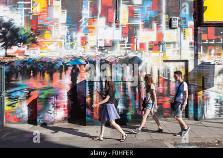 Les jeunes passent devant un mur peint de couleurs vives dans la région de Camden Town, à Londres. Banque D'Images