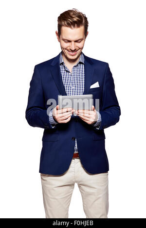 Heureux jeune homme est la lecture à partir de la tablette numérique. Isolé sur fond blanc. Banque D'Images