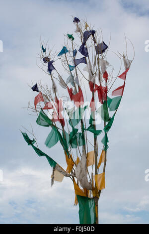 Groupe de drapeaux de prière Tibetains tissage dans le vent avec un ciel nuageux dans l'arrière-plan. Pris quelque part sur la route de l'Amitié Banque D'Images