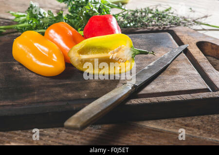 Poivrons multicolores sur bois et couteau Banque D'Images