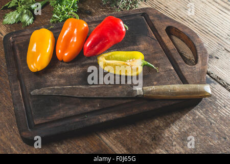 Poivrons multicolores sur bois et couteau Banque D'Images