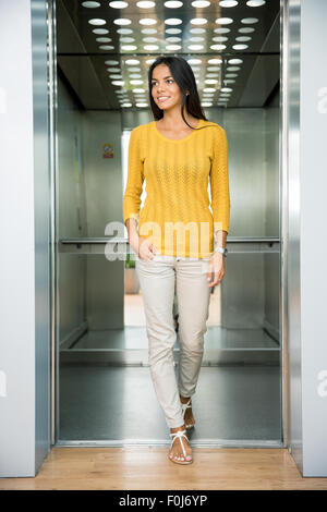 Portrait of a smiling casual businesswoman standing in ascenseur et à l'écart Banque D'Images