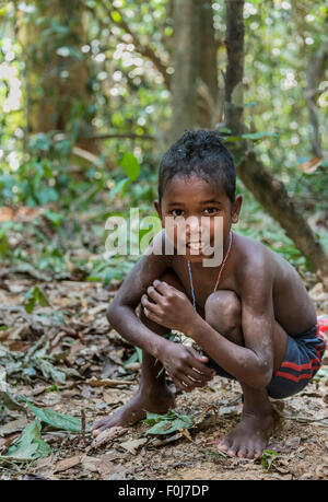 Petit garçon de la tribu Orang Asil grimaçantes, accroupis sur le sol dans la jungle, les autochtones, les communautés autochtones Volk Banque D'Images