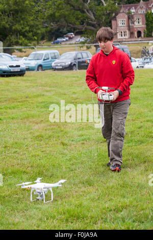 Jeune homme exploitant le drone DJI Phantom avec caméra attachée au New Forest Fairy Festival, Burley, Hampshire, Royaume-Uni en août Banque D'Images