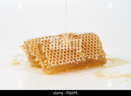 Le miel déverse sur morceau de matières Honey comb Banque D'Images