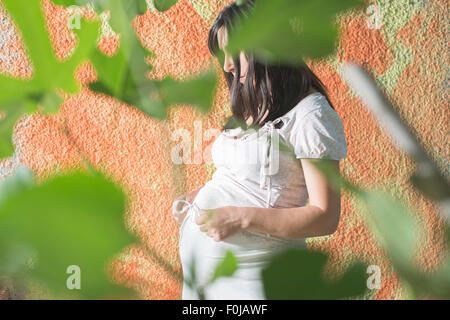 Les femmes enceintes à l'avant du mur orange. Robe blanche Banque D'Images