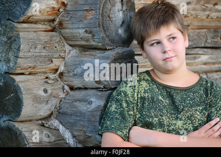 Teen Boy in camouflage se trouve près de mur en bois Banque D'Images