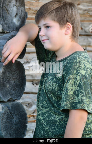 Teen Boy in camouflage se trouve près de mur en bois Banque D'Images