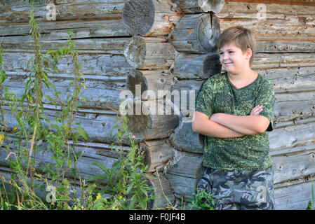 Teen Boy in camouflage se trouve près de mur en bois Banque D'Images