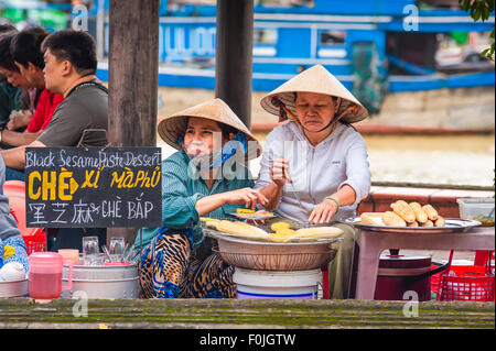 Hoi an Street food, vue de deux femmes vietnamiennes grillant du maïs sucré le long du front de mer à Hoi an, au centre du Vietnam. Banque D'Images