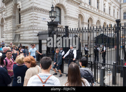 Les touristes qui pose pour des photos avec la police aux portes à l'entrée de Downing Street, London England UK Banque D'Images