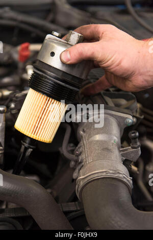 Un mécanicien de voiture s'adapte à un nouveau filtre à huile d'une voiture pendant la maintenance de routine. Banque D'Images