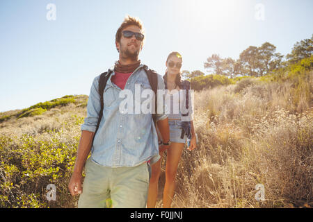 Image de jeune homme randonnée dans les montagnes avec sa petite amie. Couple en train de marcher en descente sur les jours ensoleillés. Banque D'Images