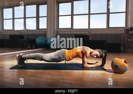 Jeune femme faisant de l'exercice musculaire de base sur Tapis de fitness dans la salle de sport. Mettre en place les femmes de faire des tractions au cours de la formation dans la santé Banque D'Images