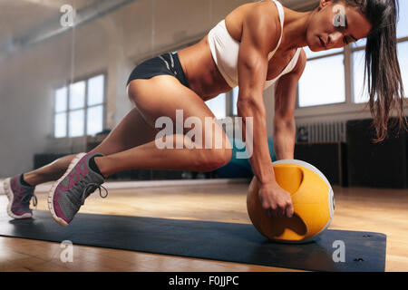 Femme musculaire intense faisant de l'exercice dans la salle de sport de base. Des femmes faisant de l'exercice de base sur Tapis de fitness avec kettlebell dans les clu Banque D'Images