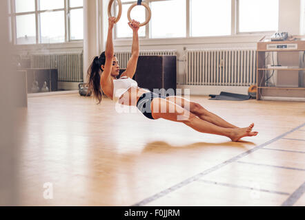 Jeune femme fit tirer sur les anneaux de gymnastique. Woman exercising on fitness musculaire. Banque D'Images