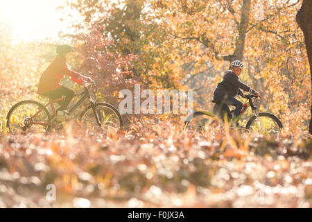 Boy and girl riding bikes dans les feuilles d'automne Banque D'Images