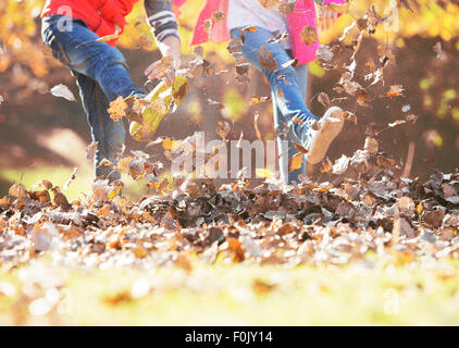 Garçon et fille les coups de pied dans les feuilles d'automne Banque D'Images