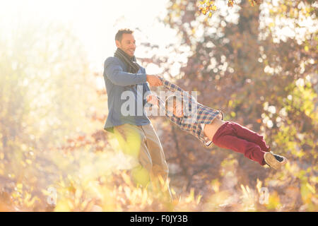 Spinning père fils parmi les feuilles d'automne Banque D'Images