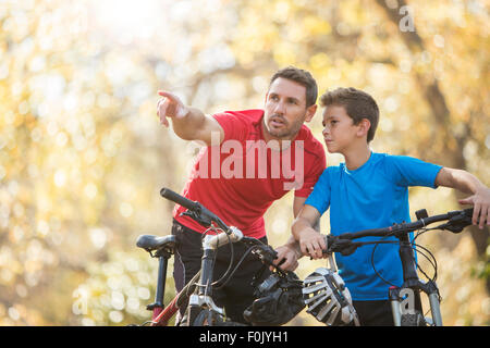 Père pointant et expliquer à son on mountain bikes Banque D'Images