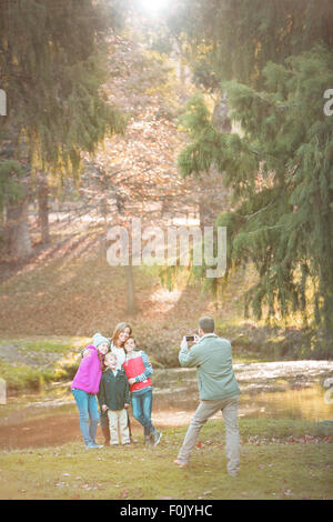 Père photographing family avec camera phone in park Banque D'Images