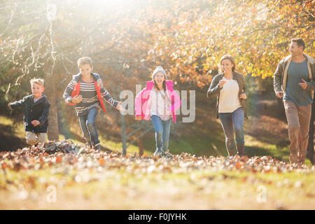 L'exécution de la famille dans le parc avec les feuilles d'automne Banque D'Images